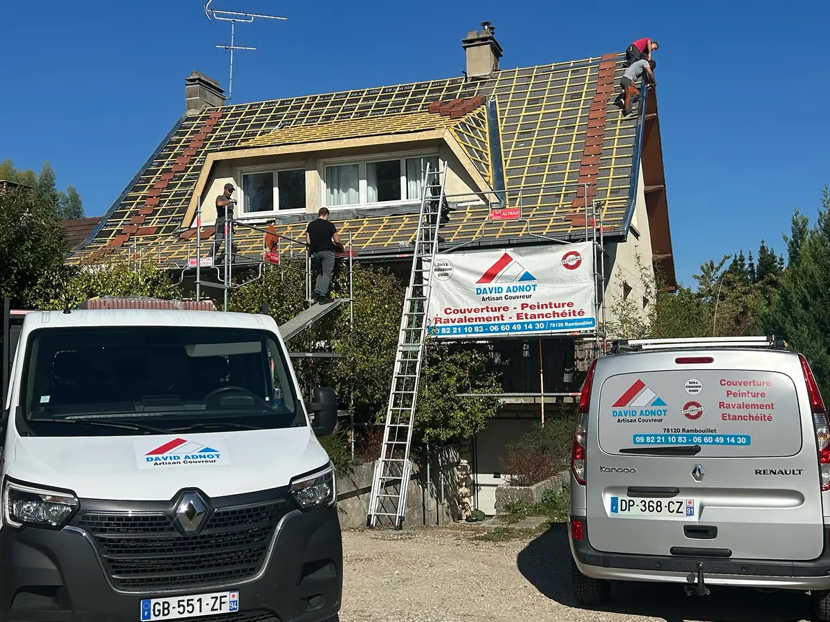 L'équipe de David Adnot, artisan couvreur, en pleine rénovation de toiture dans les Yvelines : écran sous-toiture et liteaux posés, échafaudage et camionnettes devant le chantier