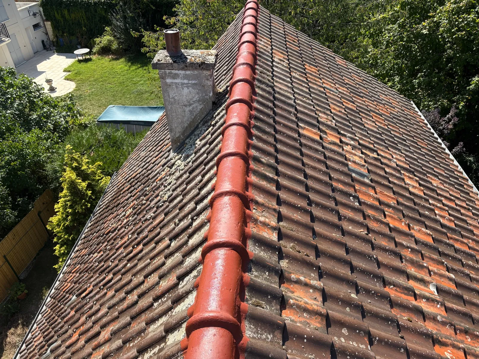 Faîtières neuves en terre cuite rouge sur une toiture en tuiles anciennes à Rambouillet