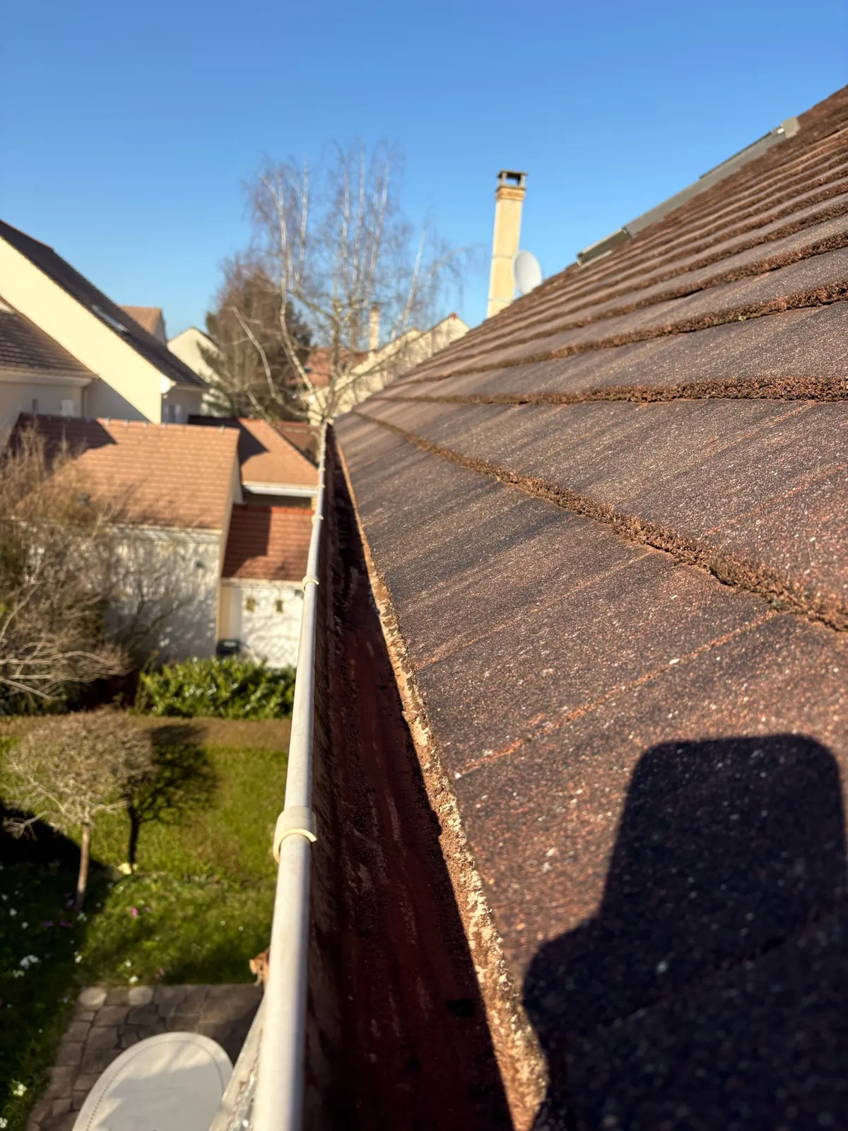 Gouttière remplie de mousse le long d'une toiture en bardeaux à Saint-Rémy-lès-Chevreuse